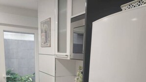 Een moderne keuken met een witte koelkast, een roze kom en potplanten.