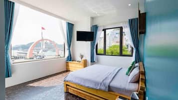 Une chambre d’hôtel moderne avec un grand lit, une télévision et une vue sur un pont et le paysage urbain.