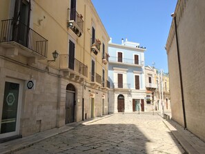 A narrow cobblestone street lined with historic buildings, featuring balconies and traditional architecture.