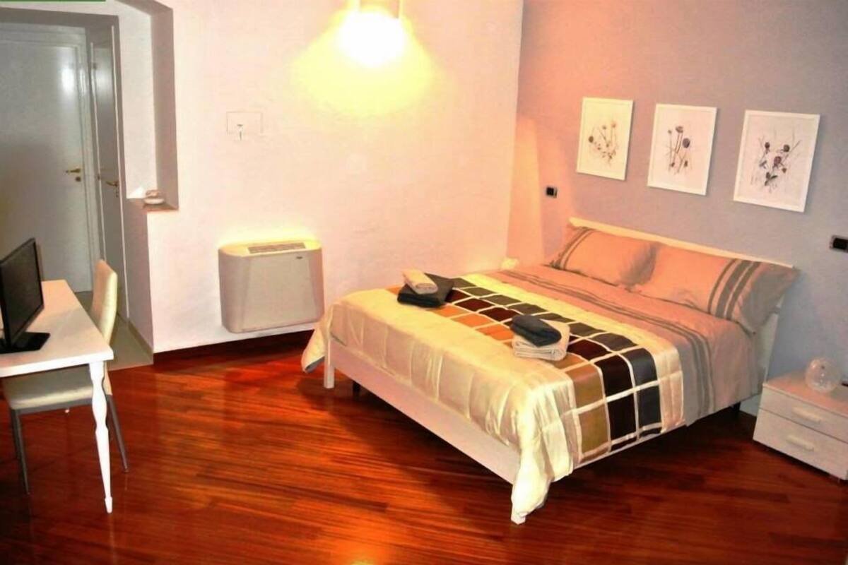 Een slaapkamer met een bed, nachtkastje, stoel en bureau.
