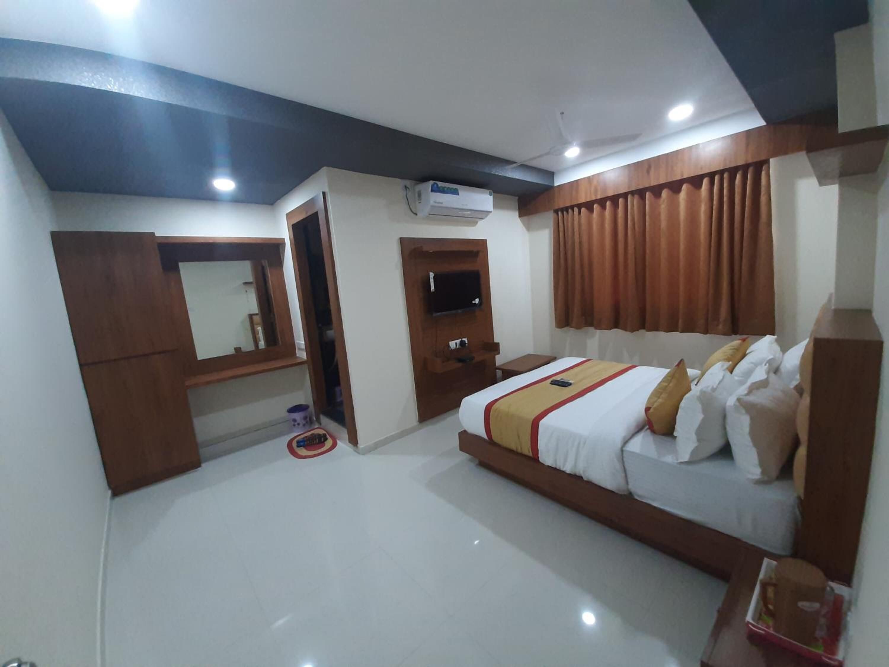 A hotel room with a bed, a TV, a wardrobe, and a ceiling fan.