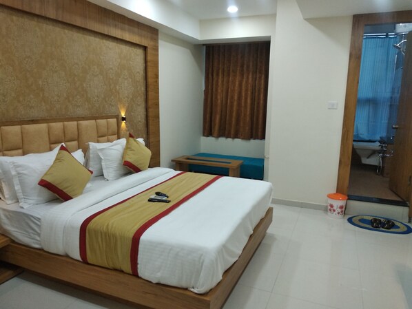 A neatly made bed with a headboard, a bedside table, and a mirror reflecting a bathroom.