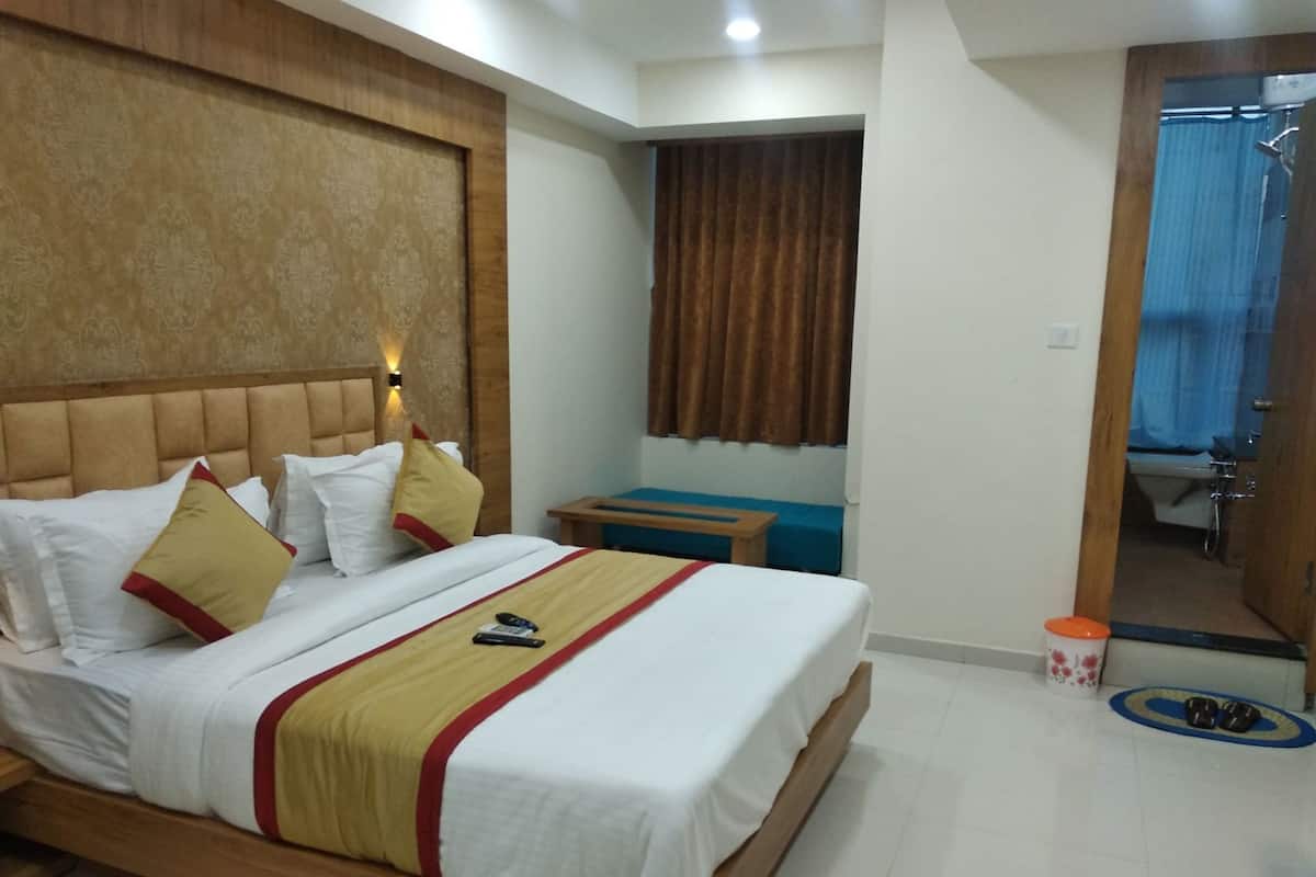 Una habitación de hotel con cama, mesita de noche y espejo.