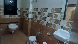 Une salle de bain équipée de toilettes, d’un lavabo, d’une douche et de carreaux décoratifs.
