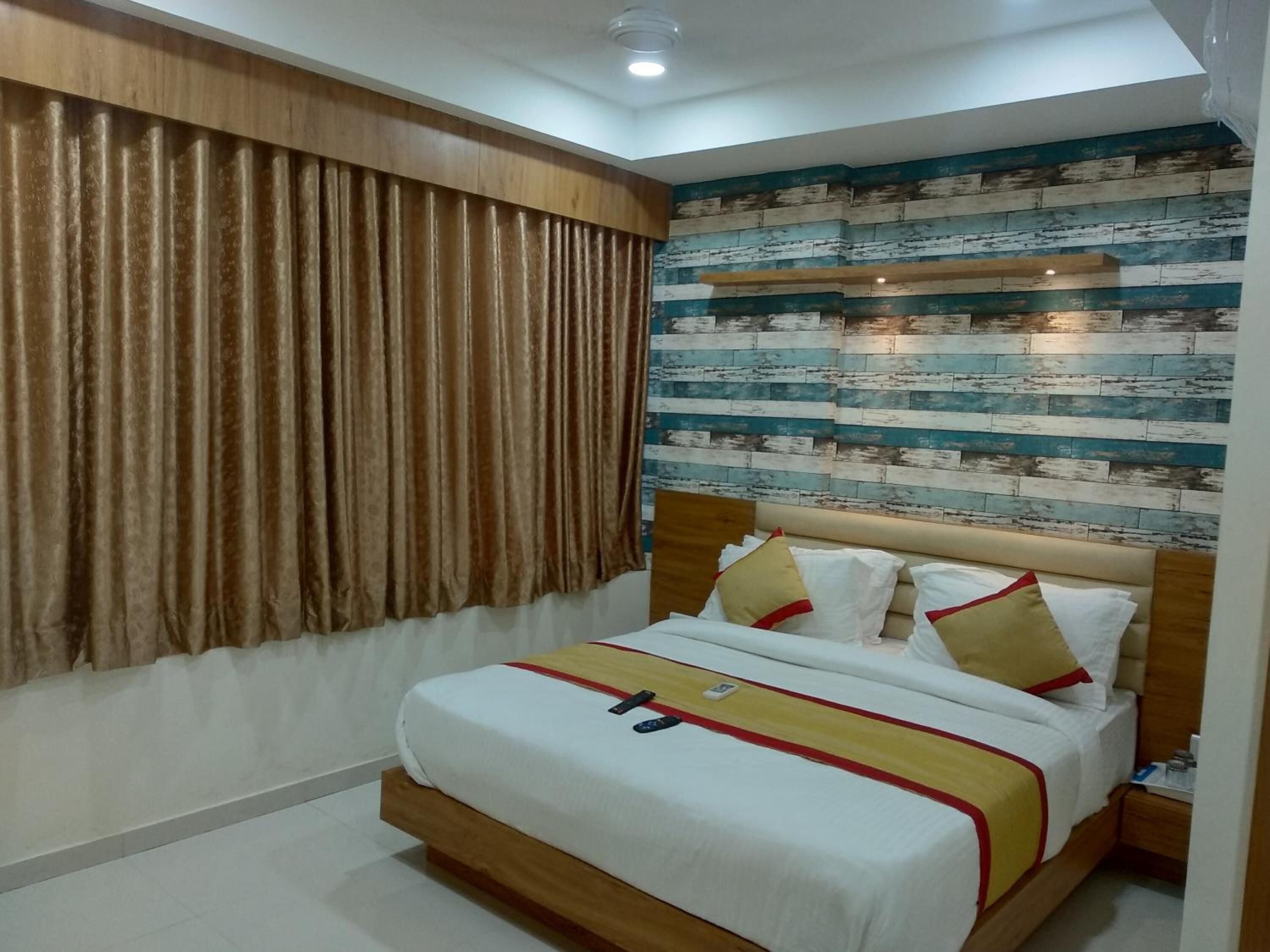 A bedroom with a bed, curtains, a headboard with a decorative panel, and a wall with a wooden plank design.