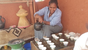 A person pouring liquid from a kettle into cups on a table. - Lalibela Roha Tour (Lalibela)
