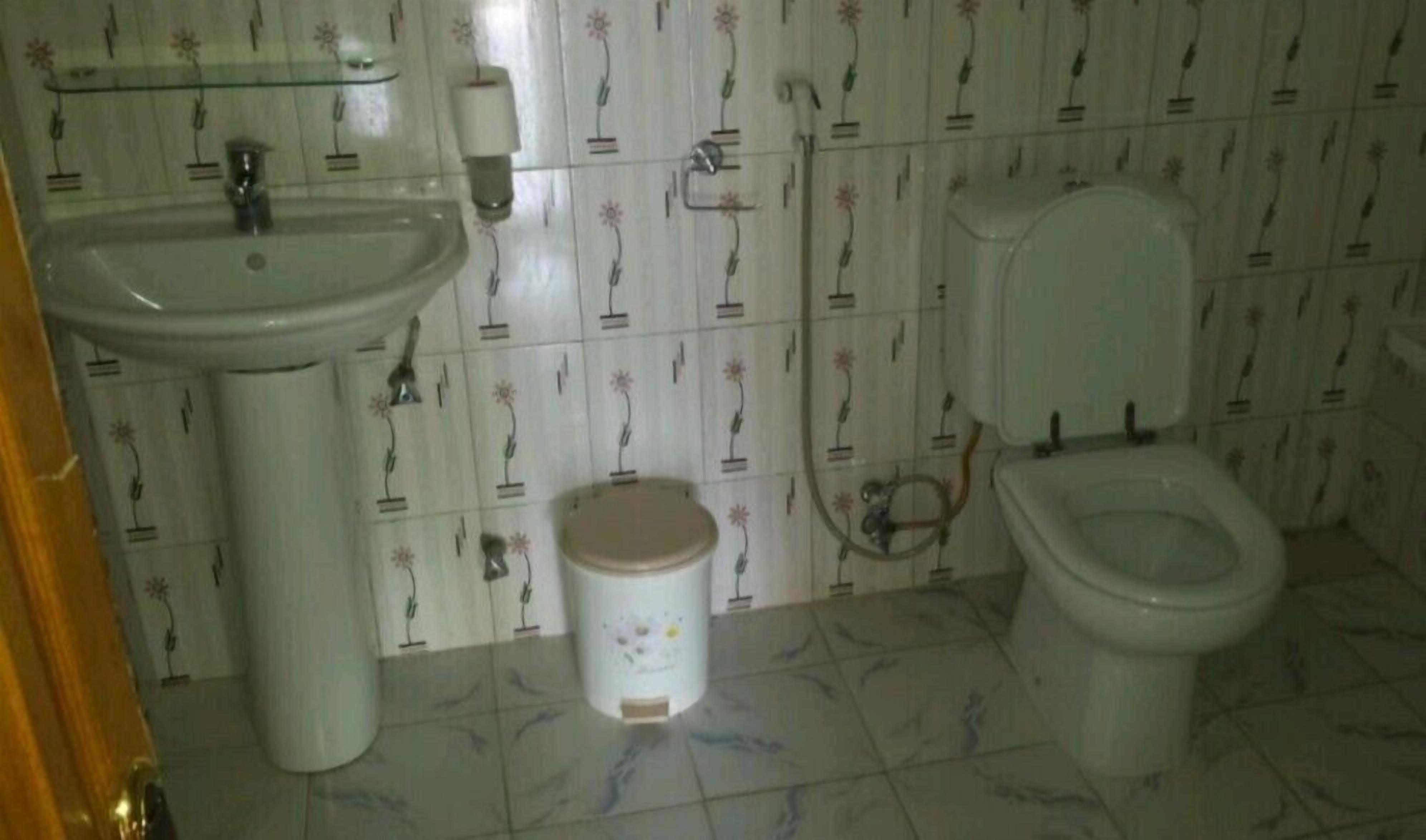Une salle de bain équipée d’un lavabo, de toilettes et d’une petite poubelle.