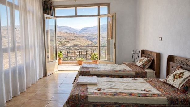 A bedroom with two beds, a balcony with potted plants, and a view of a mountainous landscape. - Lalibela Roha Tour (Lalibela)
