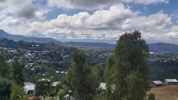 Un paisaje montañoso con casas dispersas y cielo despejado.