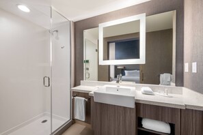 Experience a sleek and contemporary bathroom with a glass-enclosed shower, modern sink, and large mirror.