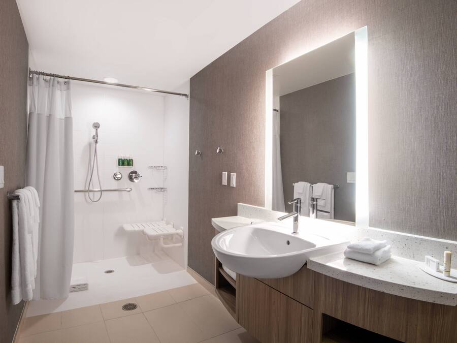 A modern bathroom with a walk-in shower, a large mirror, and a double sink vanity.