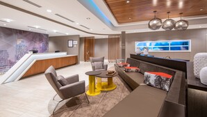 A modern hotel lobby with a reception desk, seating area, and a large window offering a view. - SpringHill Suites by Marriott Denver Parker (Parker)