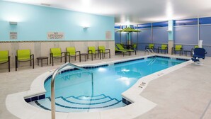 An indoor swimming pool with a blue and white tiled design, surrounded by green chairs and a lifeguard station. - SpringHill Suites by Marriott Denver Parker (Parker)