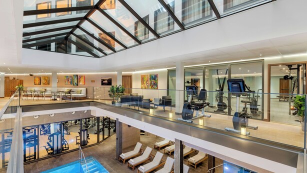 Un hôtel à plusieurs niveaux, avec un intérieur comprenant une piscine, une salle de sport, des espaces de détente et des œuvres d’art.