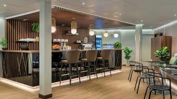 Uma área de bar moderna com detalhes em madeira, banquetas e iluminação pendente.