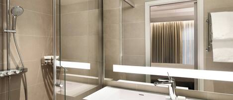 A modern bathroom with a glass-enclosed shower, a white sink, and a large mirror.