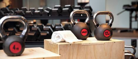 Kettlebells of different weights on wooden boxes in a gym setting.