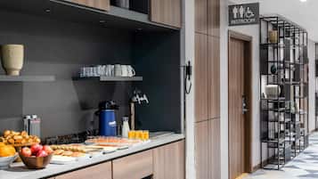 A modern hotel room with a breakfast bar, a sign indicating a restroom, and a patterned floor.