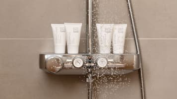 Ducha con varios frascos de champú, acondicionador, loción corporal y gel de baño.