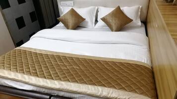 A neatly made bed with a quilted headboard, two pillows, and a matching bedspread.