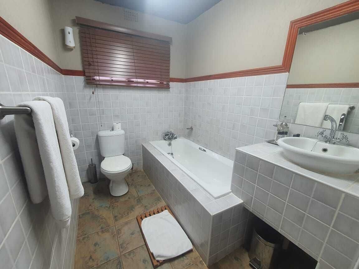 A bathroom with white tiled walls, a bathtub, a toilet, and a sink.