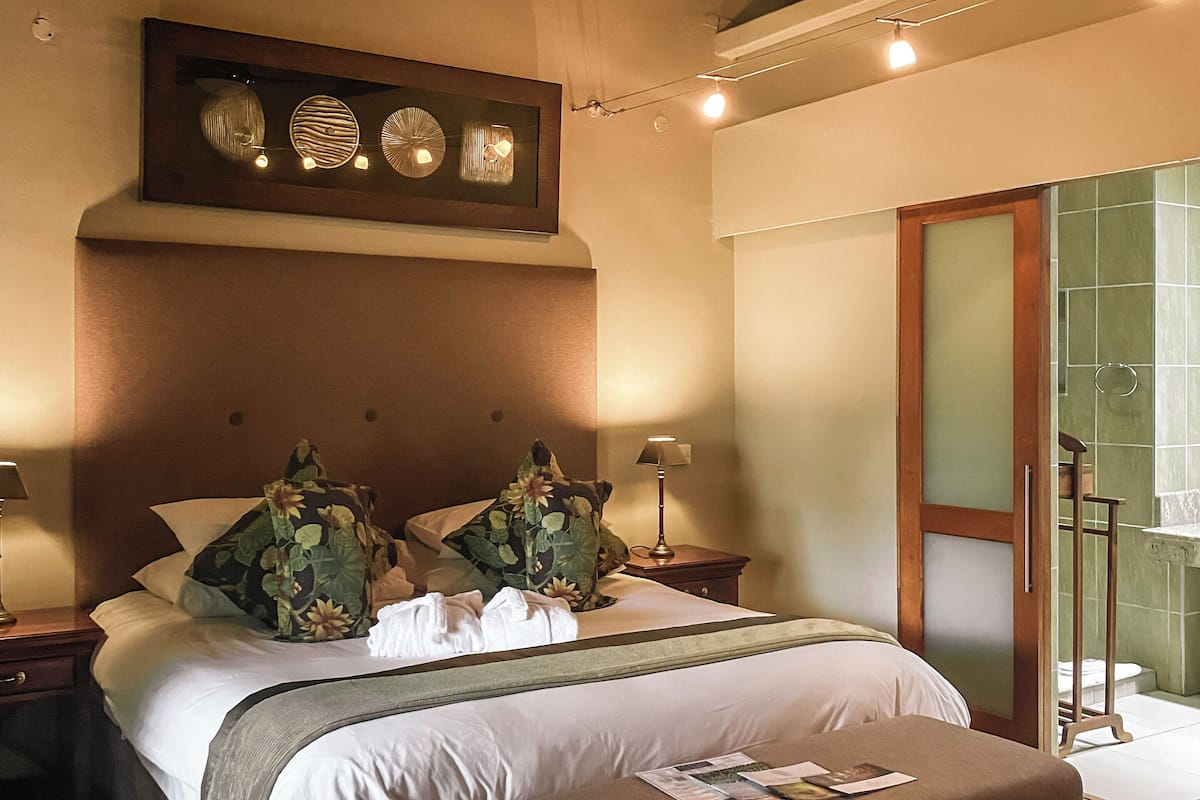 A well-lit bedroom with a large bed, a ceiling fan, and a nightstand with a lamp.