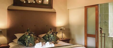 A well-lit bedroom with a large bed, a ceiling fan, and a nightstand with a lamp.