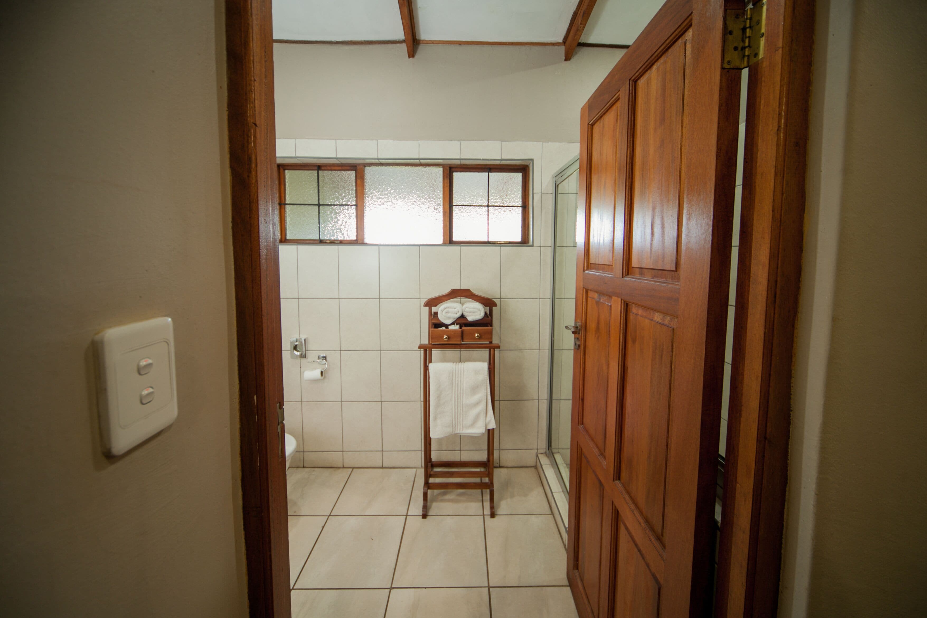 Une salle de bain avec une porte en bois, un porte-serviettes et une fenêtre.