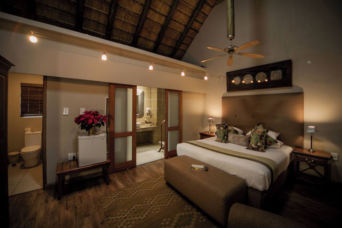 A spacious bedroom with a large bed, a ceiling fan, and a nightstand with a lamp.