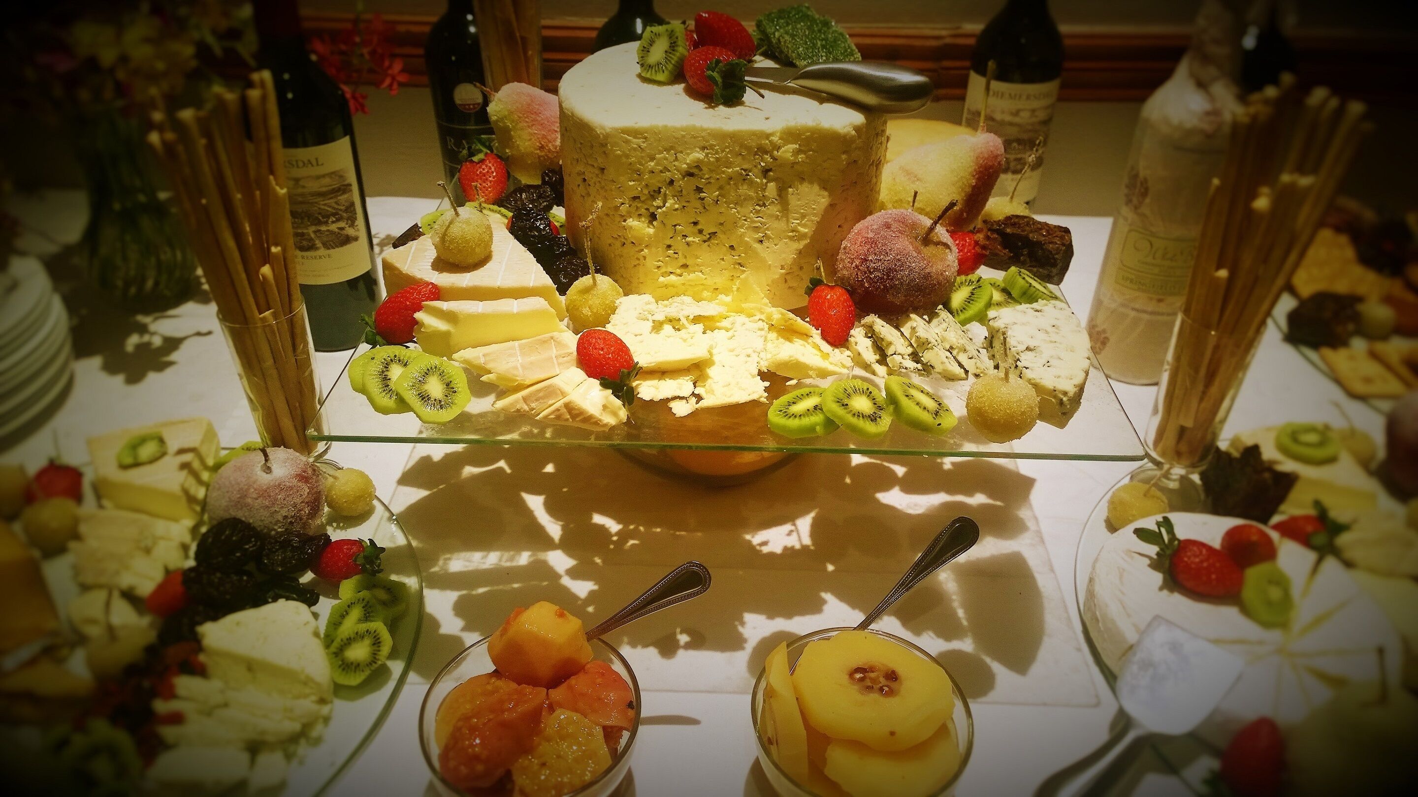 A dessert table with various fruits, cheeses, and a cake.
