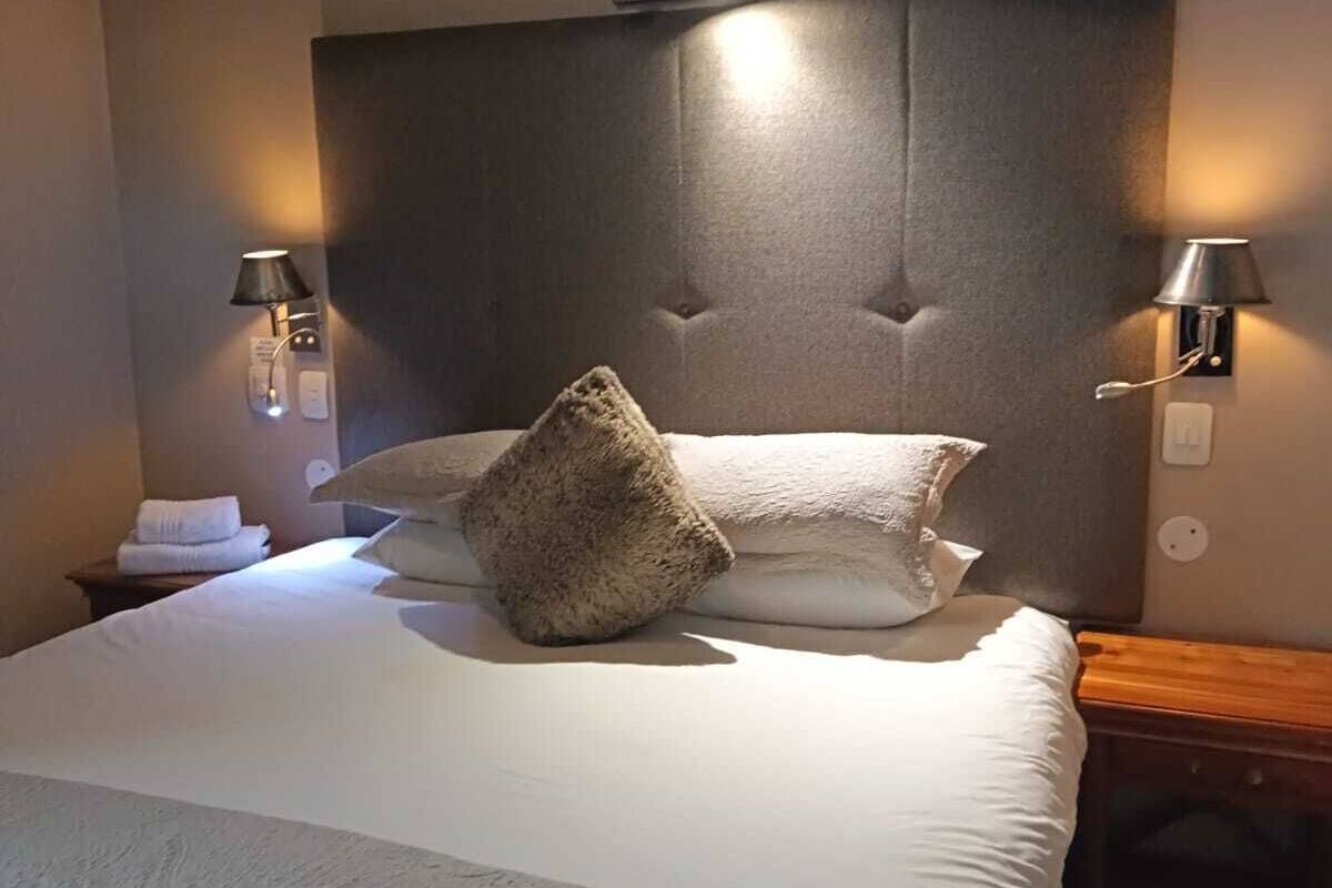 A neatly made bed with a tufted headboard, two bedside lamps, and a small table with a lamp.