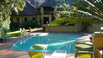 Una piscina al aire libre, sombrillas, tumbonas