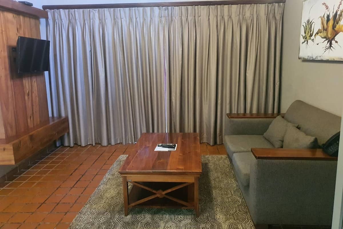 A living room with a wooden coffee table, a grey sofa, and a patterned rug.