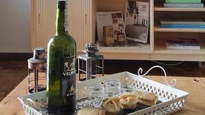 A living room with a TV, framed pictures, a bottle of wine, and a tray with pastries. - Flower House 🏡🌻 (Santo Tirso)