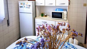 A compact kitchen with a refrigerator, microwave, and cabinets. - Flower House 🏡🌻 (Santo Tirso)