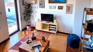 A living room with a TV, wooden coffee table, and a bookshelf. - Flower House 🏡🌻 (Santo Tirso)