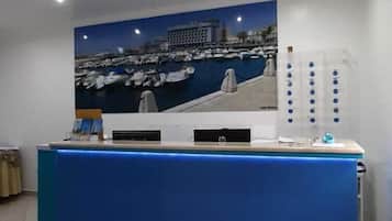 A reception desk with a cityscape painting above it, a blue counter, and a tiled floor.