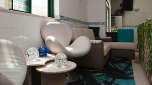 Una sala moderna con un sofá curvo, una pequeña mesa redonda con esferas de cristal decorativas y una alfombra estampada.