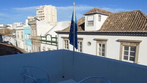Una terraza en la azotea con un asta de bandera, una mesa y dos sillas.