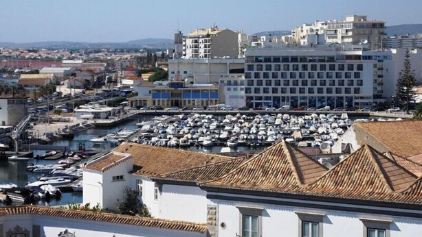 Un puerto deportivo con numerosas embarcaciones amarradas, rodeado de edificios con techos de tejas tradicionales.