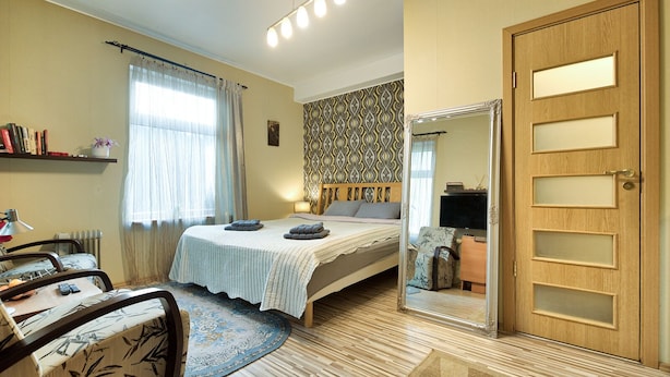 A bedroom with a bed, bedside table, chair, and a mirror. - Quiet romantic place Tartu Home Apts. (Tartu)