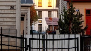 A row of houses with a white facade and a red roof, a black gate, and a tree in the foreground. - Quiet romantic place Tartu Home Apts. (Tartu)