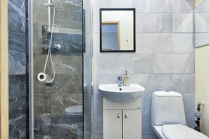 A bathroom with a glass-enclosed shower, a white sink, and a toilet.