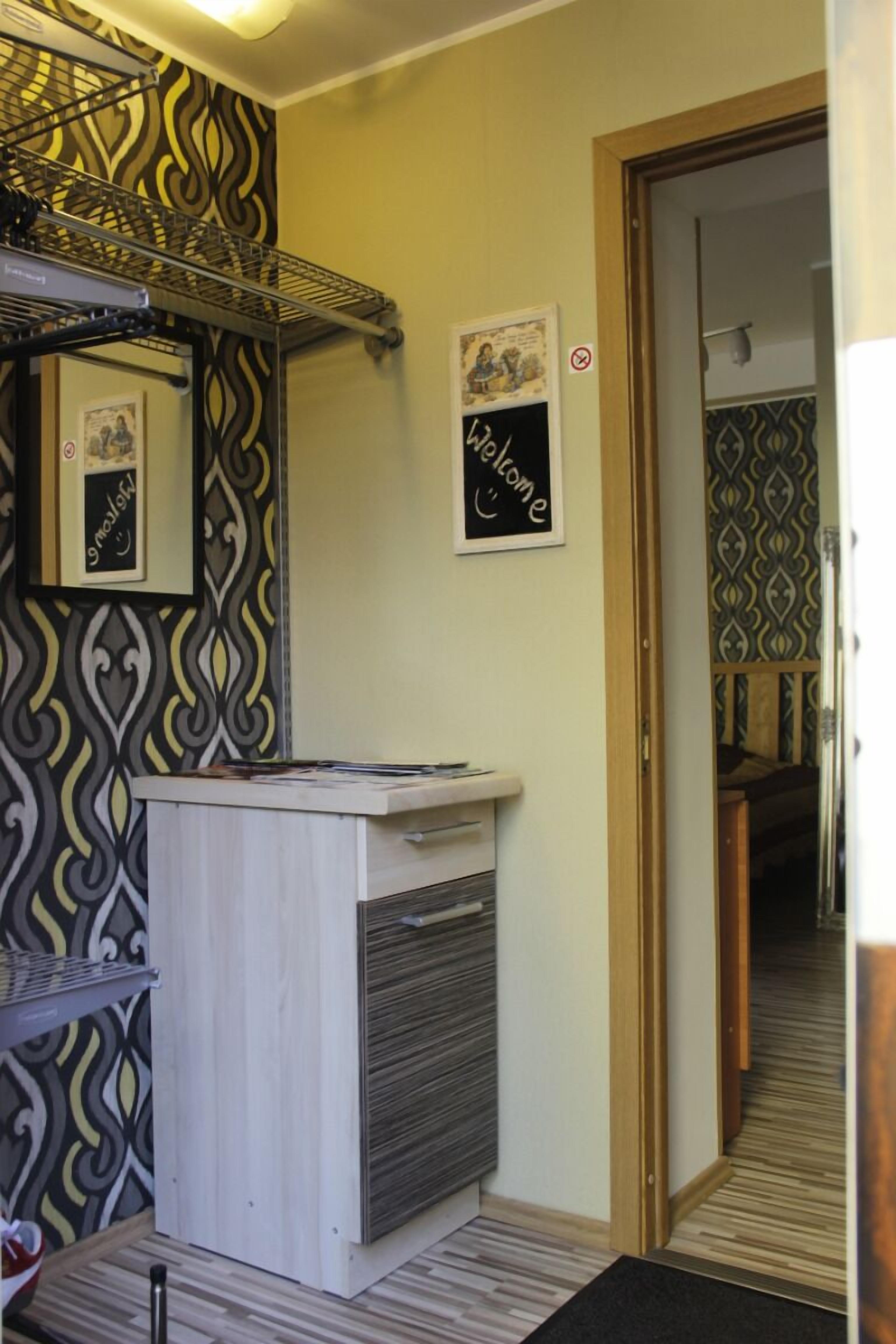 A bathroom with a patterned wall, a towel rack, a sink, and a door leading to another room.