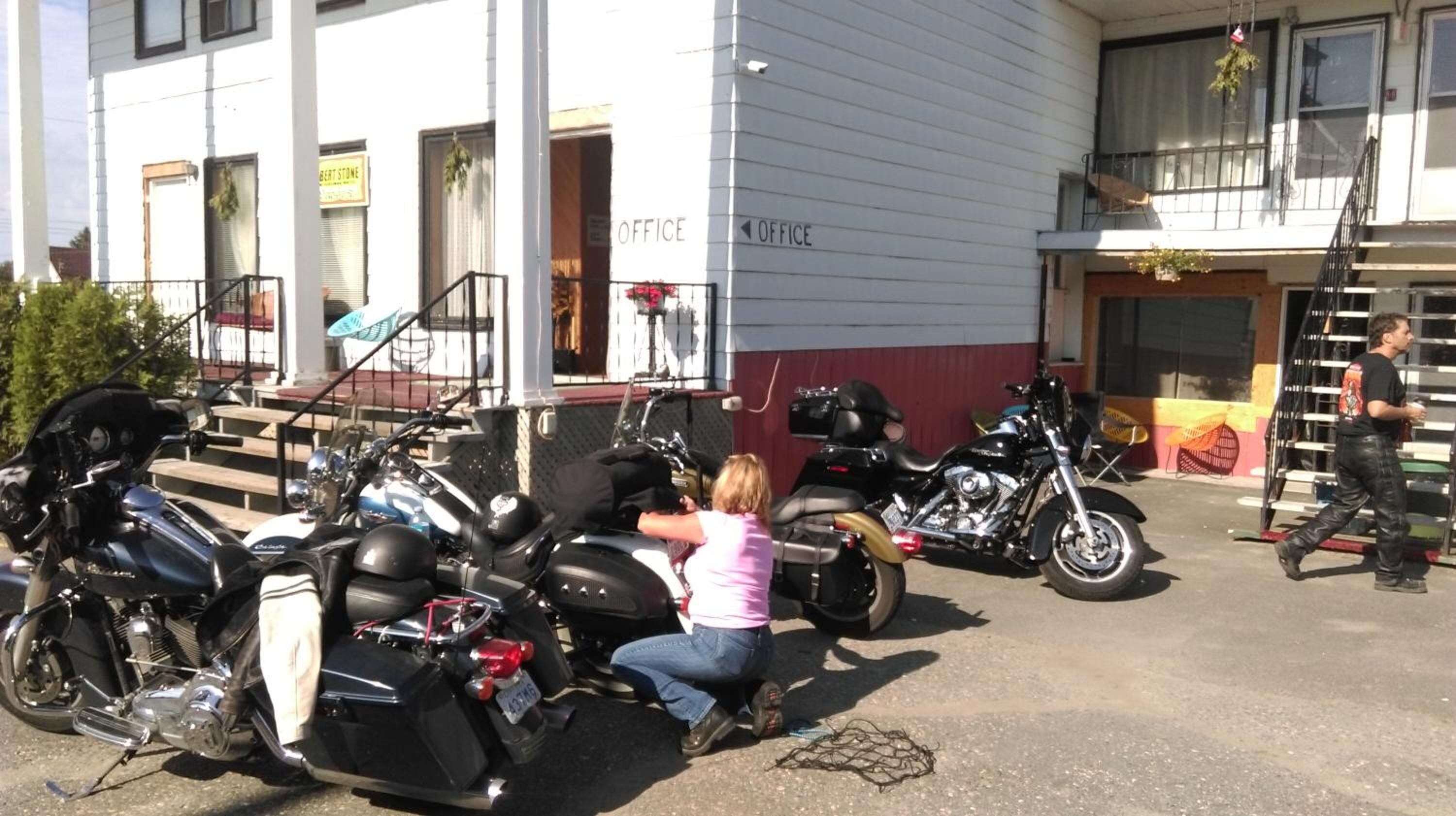 Un bâtiment avec des panneaux indiquant « BUREAU », un escalier et des motos garées.