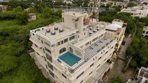 Un hôtel à plusieurs étages doté d’une piscine et d’une terrasse sur le toit.