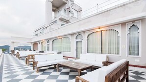 Une terrasse sur le toit avec un sol à carreaux, des sièges blancs rembourrés et une table en bois.