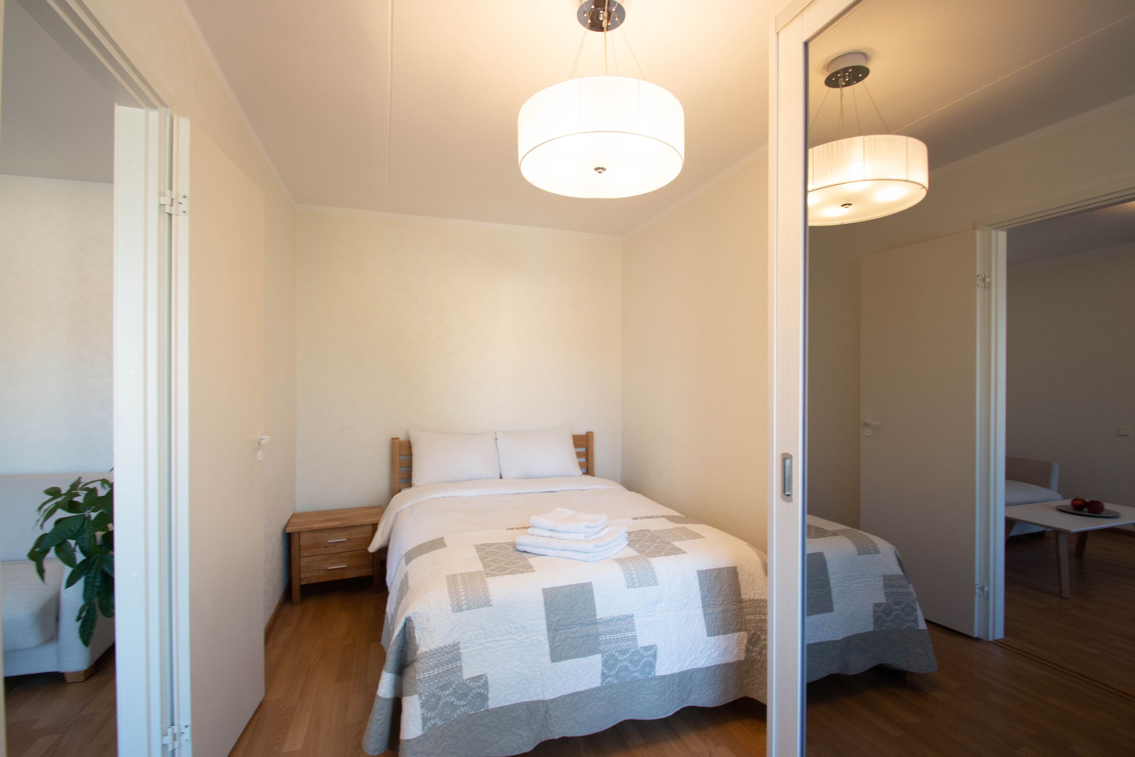 A bedroom with a bed, bedside table, and a mirror.