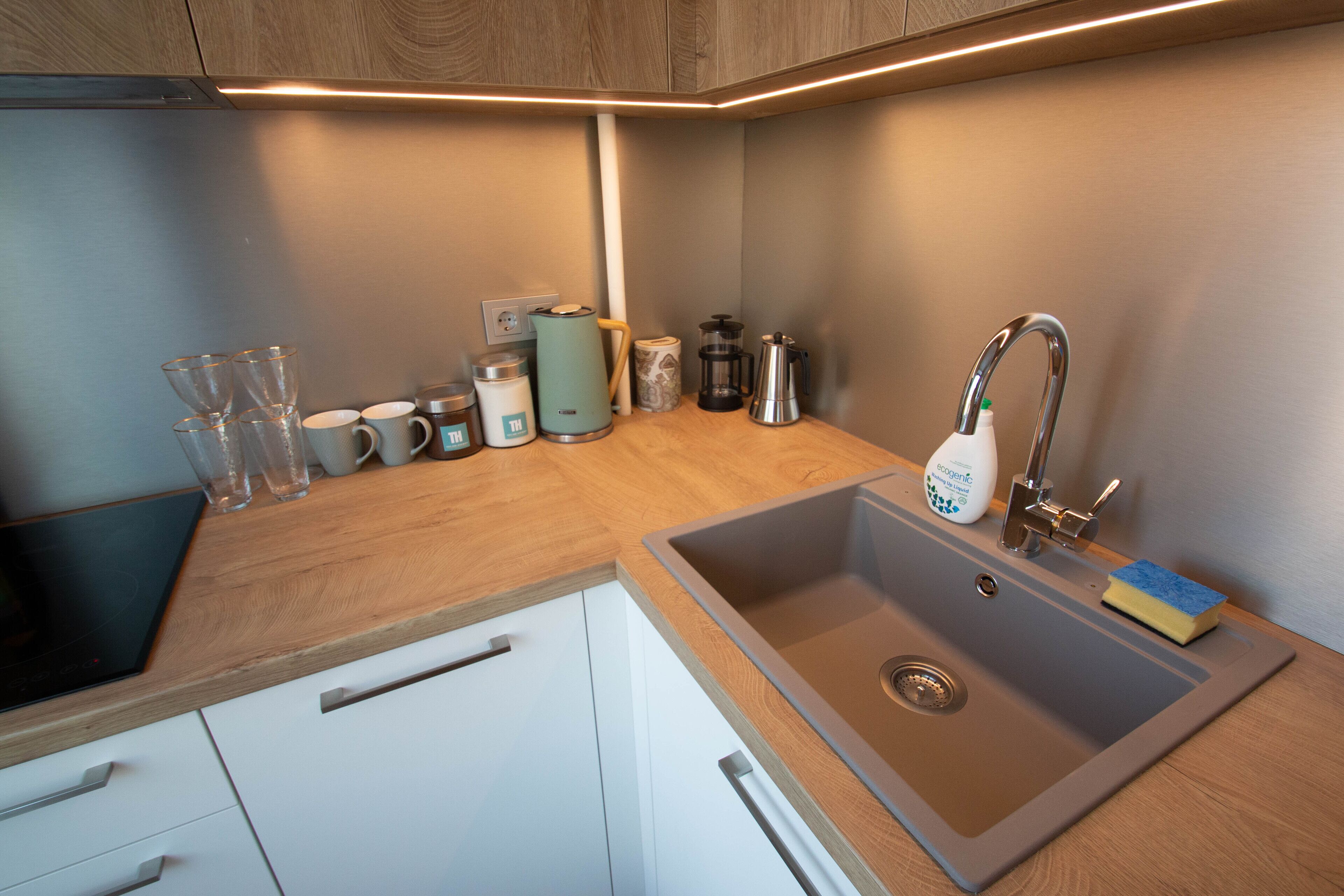 Una cocina moderna con un lavamanos de acero inoxidable, encimera de madera y armarios blancos.