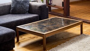 Una sala de estar acogedora con un sofá gris oscuro, una mesa de centro de madera y una estantería con objetos decorativos.